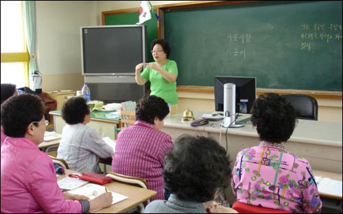 한글 수업을 진행하고 있는 할머니 정진영 강사와 수업을 진지하게 듣고 있는 할머니 수강생들 